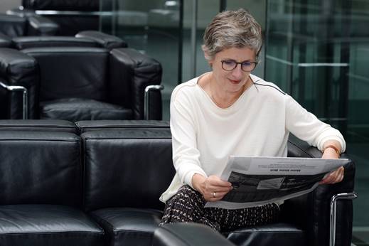 Britta Haßelmann liest eine Zeitung auf einer Couch