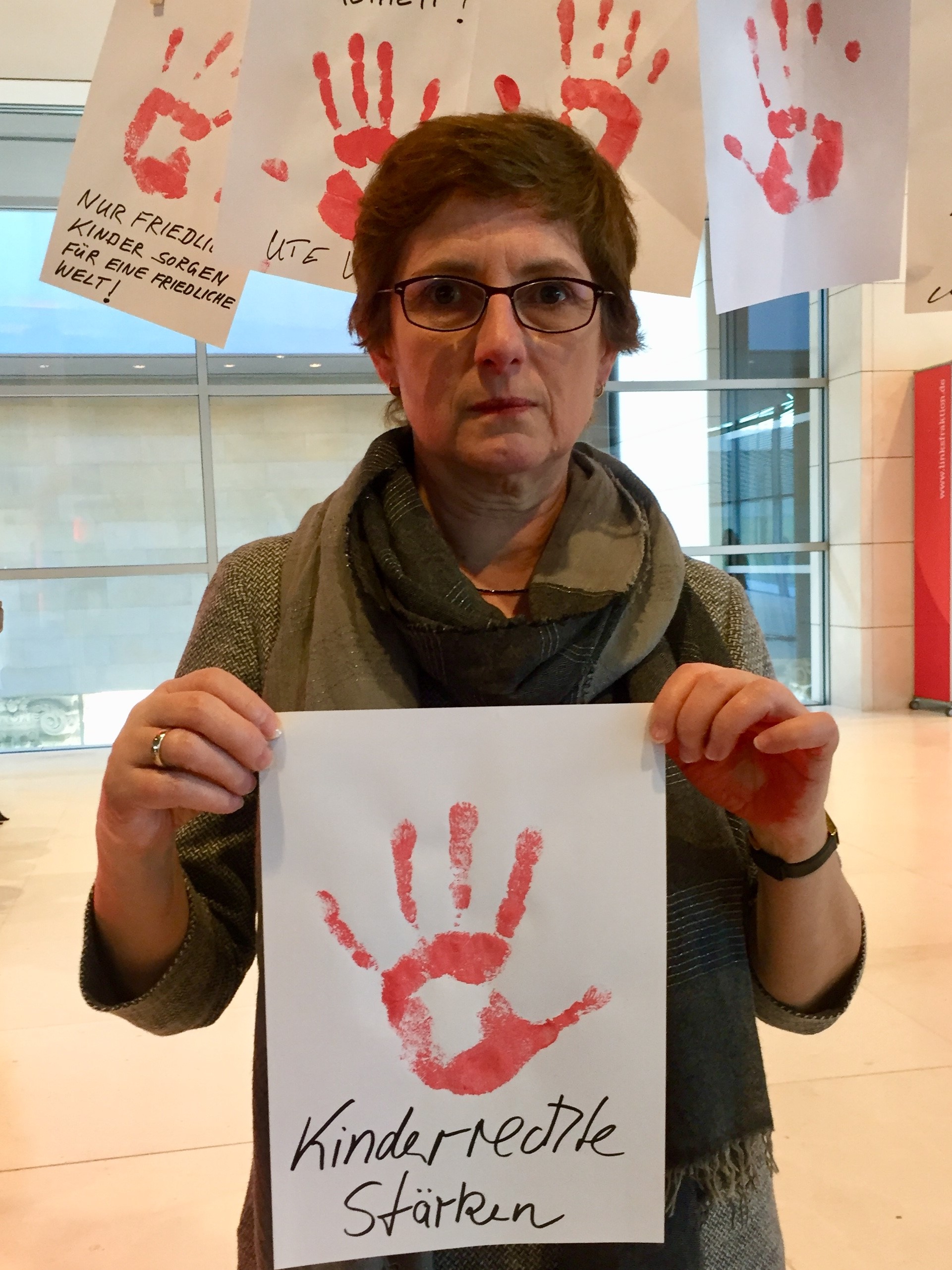 Britta Haßelmann hält ein Papier mit einem roten Handabdruck und der Aufschrift "Kinderrechte stärken" in die Kamera
